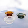 Three small round glass ashtrays with matching textured bases, shown on a white surface in amber, clear, and smoky green glass.