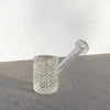 A clear Jane West Twenties Collection Glass Hand Pipe with a textured, diamond-cut bowl and a straight, angled stem, resting on a gray stone surface against a white background.