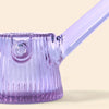 A NWTN Home close-up of a translucent lavender purple glass water pipe with a ribbed textured body and a diagonal glass mouthpiece, set against a solid pale beige background.